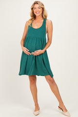 woman wearing a green ribbed maternity dress, holding her baby bump and smiling