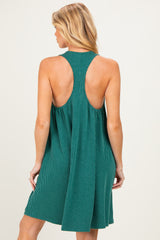woman wearing a green sleeveless maternity dress with a ribbed texture and open back, featuring a flowing silhouette