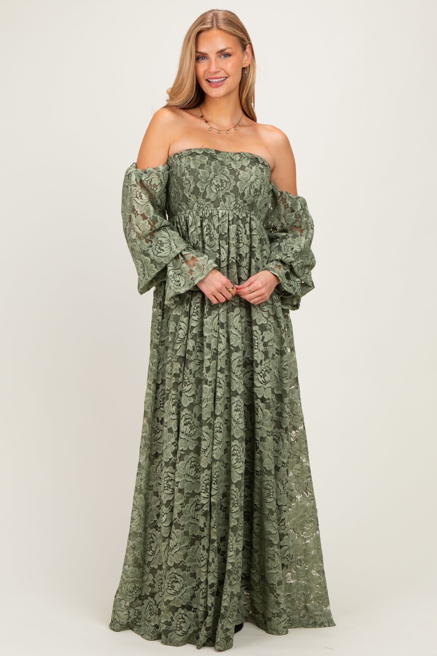 woman wearing a green off-the-shoulder lace maxi dress with puff sleeves and a cinched waist