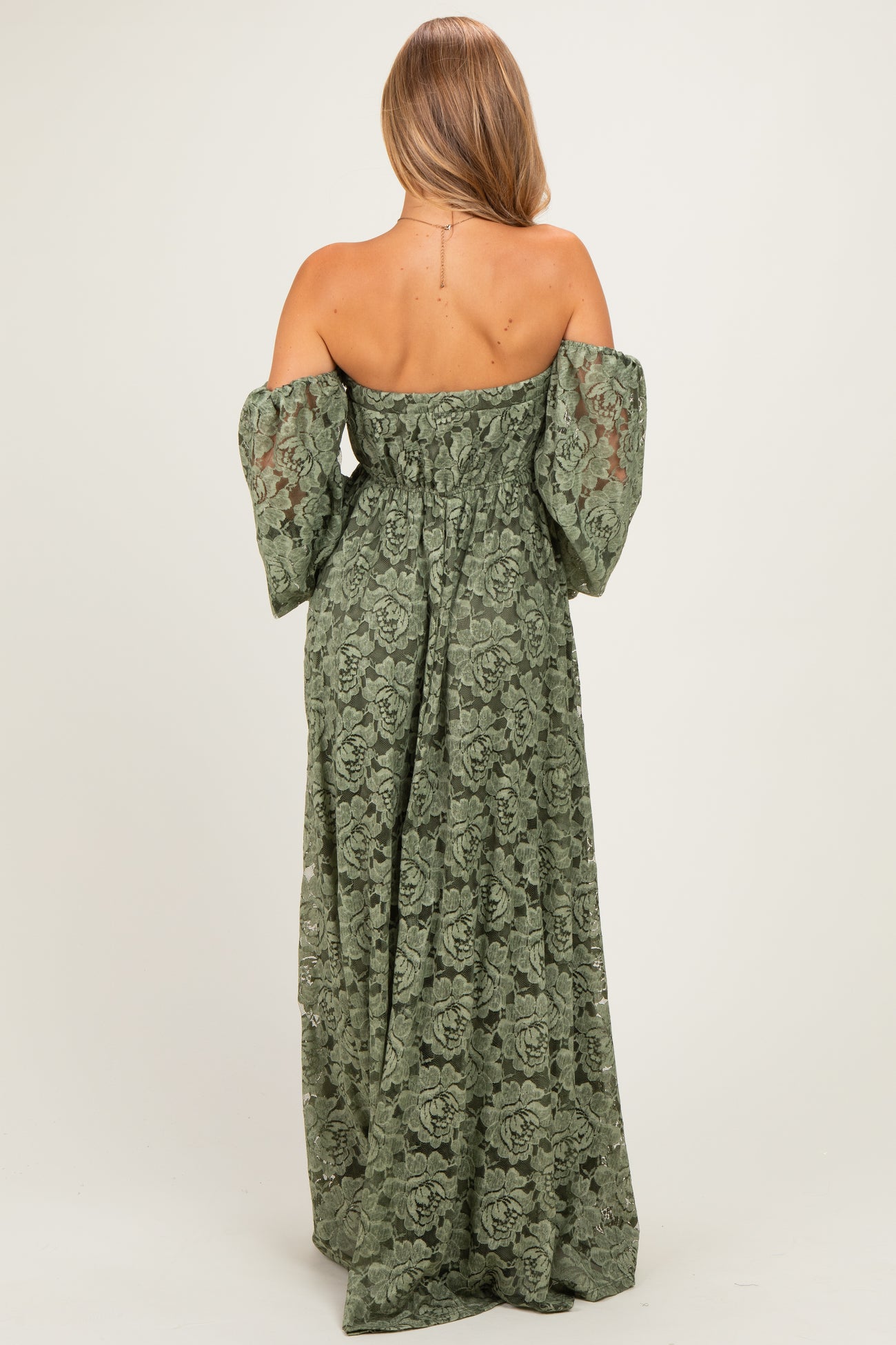 woman wearing a green off-the-shoulder maxi dress with long puff sleeves and intricate lace details