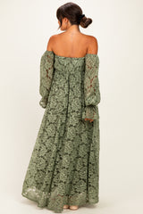 woman wearing a green lace off-the-shoulder maternity dress with long puff sleeves and a flowy silhouette