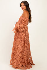 woman wearing a rust-colored lace off-shoulder maternity dress with bell sleeves and a flowing silhouette