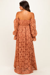 woman wearing a rust-colored off-the-shoulder lace maternity maxi dress with long puff sleeves
