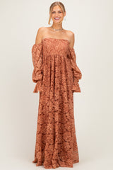 woman wearing a rust off-the-shoulder maxi dress with bell sleeves and floral lace details