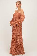 woman wearing a rust-colored off-shoulder maxi dress with puff sleeves and floral lace details