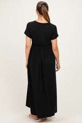 woman wearing a black short sleeve maternity maxi dress, showing a comfortable elastic waistband and flowing silhouette from the back