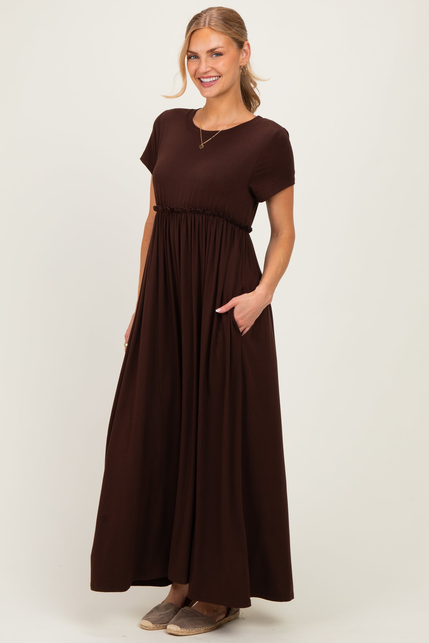 woman wearing a chocolate brown short sleeve maxi dress with a gathered waist and pockets