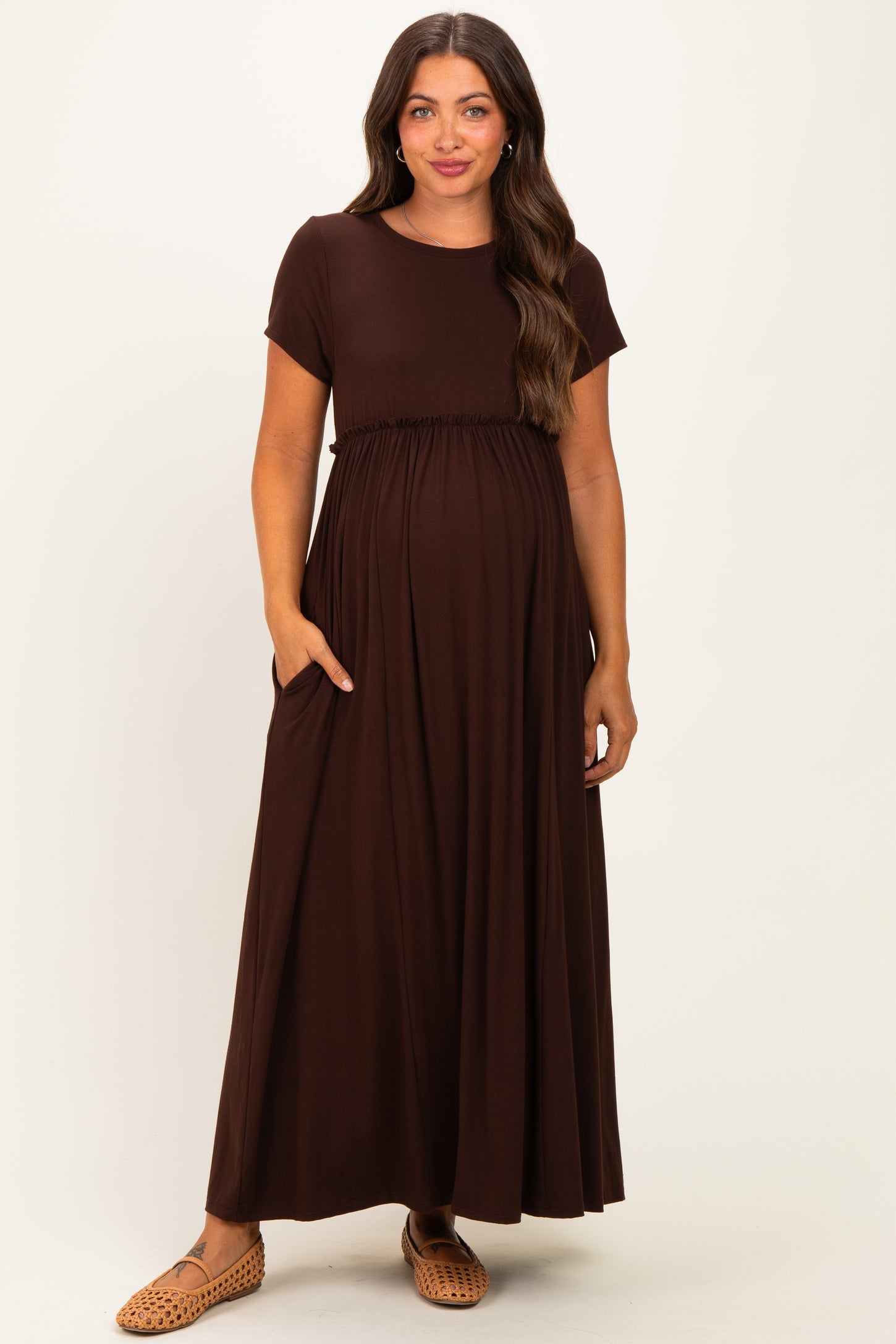 woman wearing a brown maternity maxi dress with short sleeves and pockets, showing her baby bump