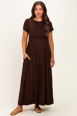 woman wearing a brown maternity maxi dress with short sleeves and pockets, showing her baby bump