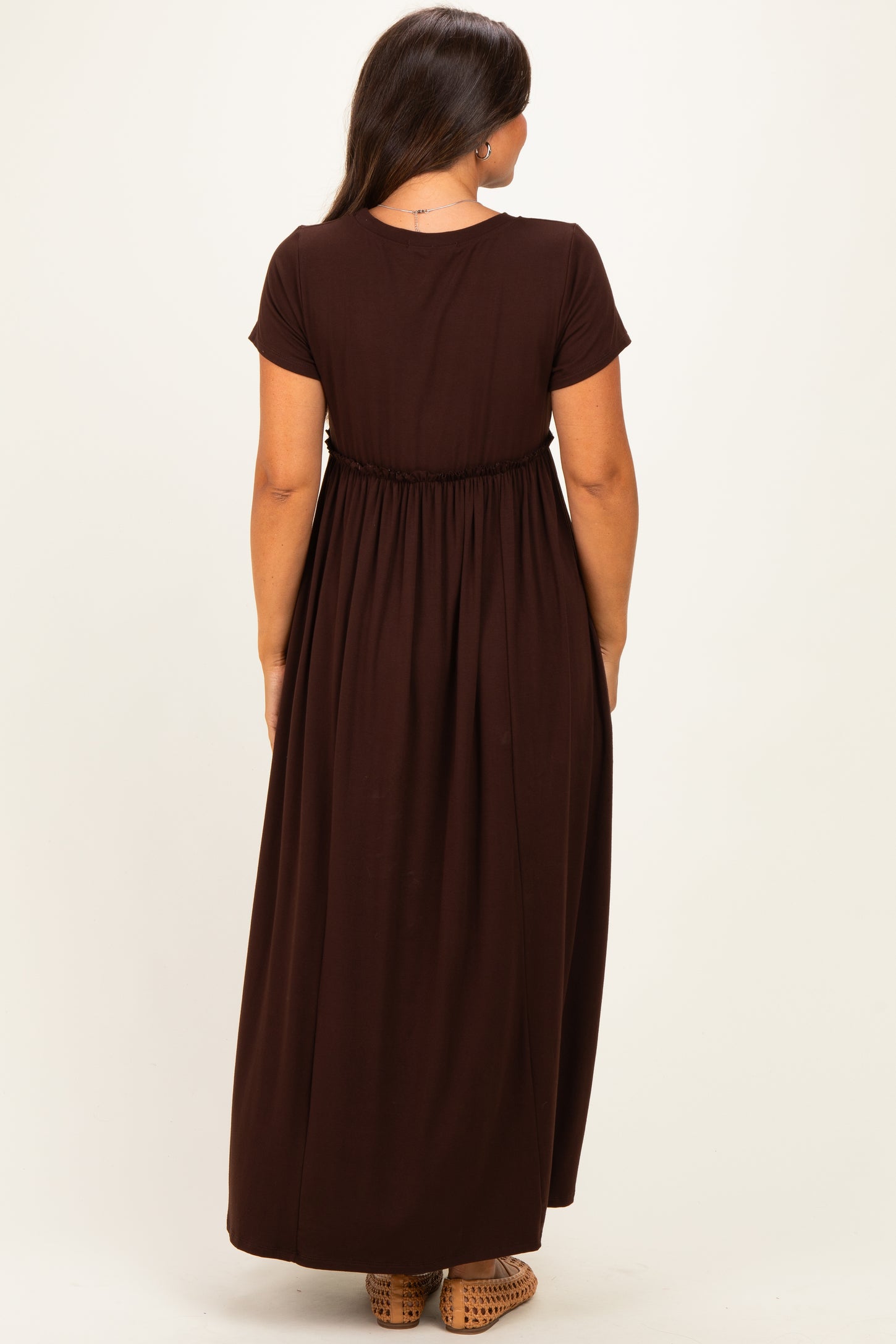 woman wearing a brown maternity maxi dress with short sleeves and an elastic waistband viewed from the back