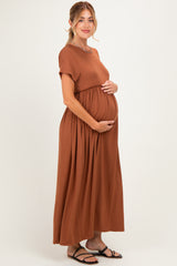 woman wearing a rust-colored short sleeve maternity dress and holding her baby bump
