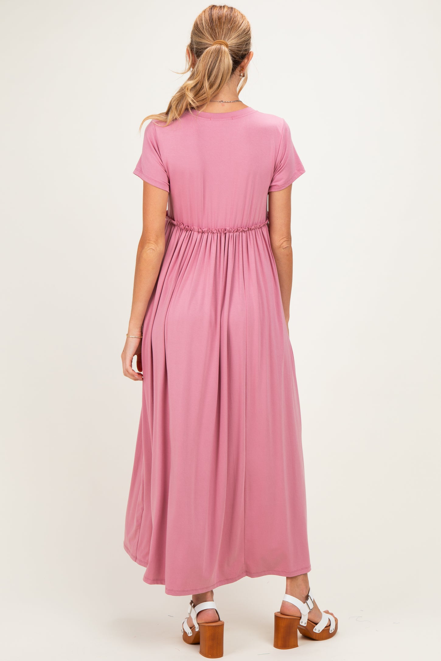 woman wearing a rose pink maternity maxi dress with a cinched waist and short sleeves, seen from the back