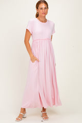 woman wearing a light pink maxi dress with short sleeves and pockets, standing on a neutral background