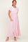 woman wearing a light pink maxi dress with short sleeves and pockets, standing on a neutral background