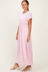 woman wearing a pink short sleeve maxi dress with an elastic waist and flowing skirt.