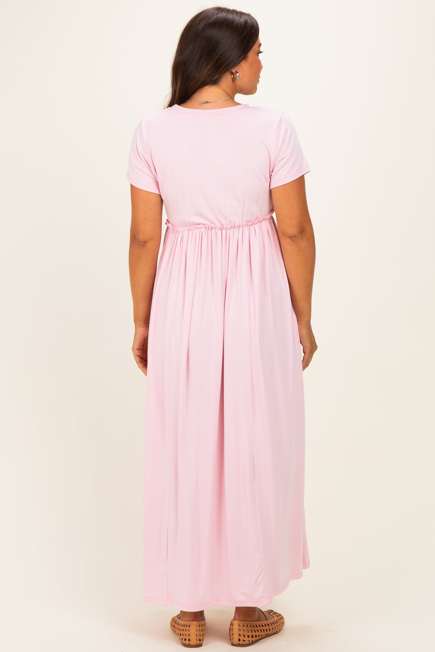 woman wearing a pink maternity maxi dress with short sleeves and an elastic waist, showing a pregnant belly from the back