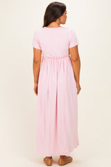 woman wearing a pink maternity maxi dress with short sleeves and an elastic waist, showing a pregnant belly from the back