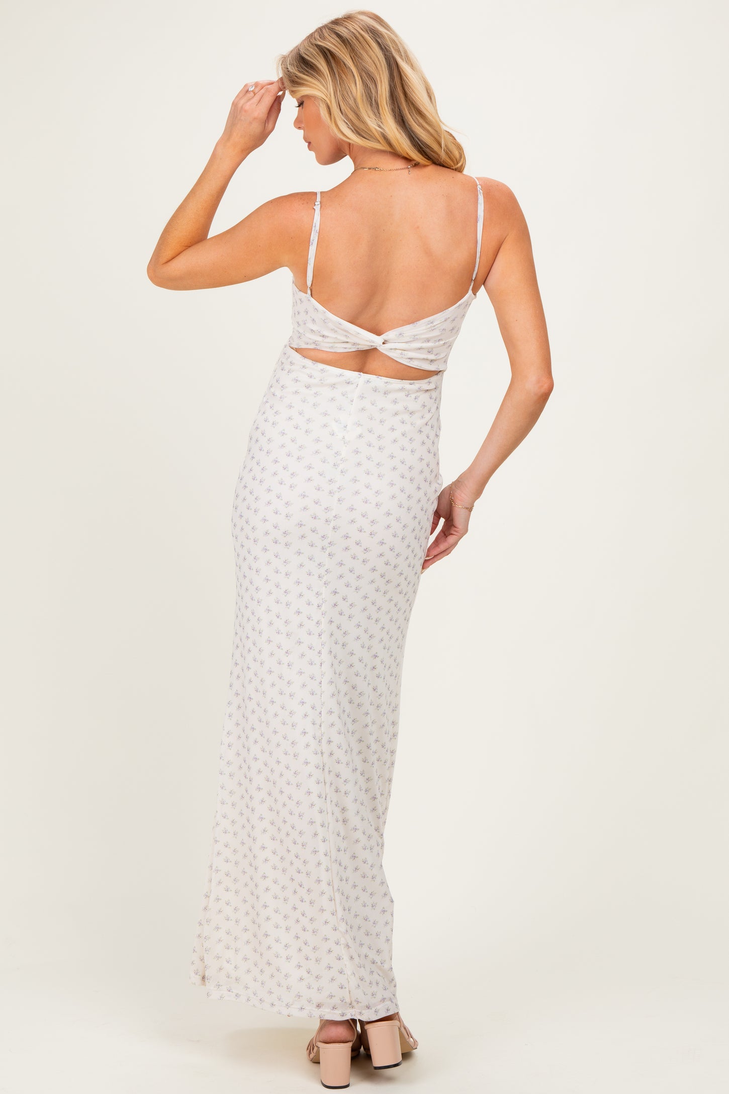 woman wearing a light pink maternity maxi dress with a floral print and open back detail