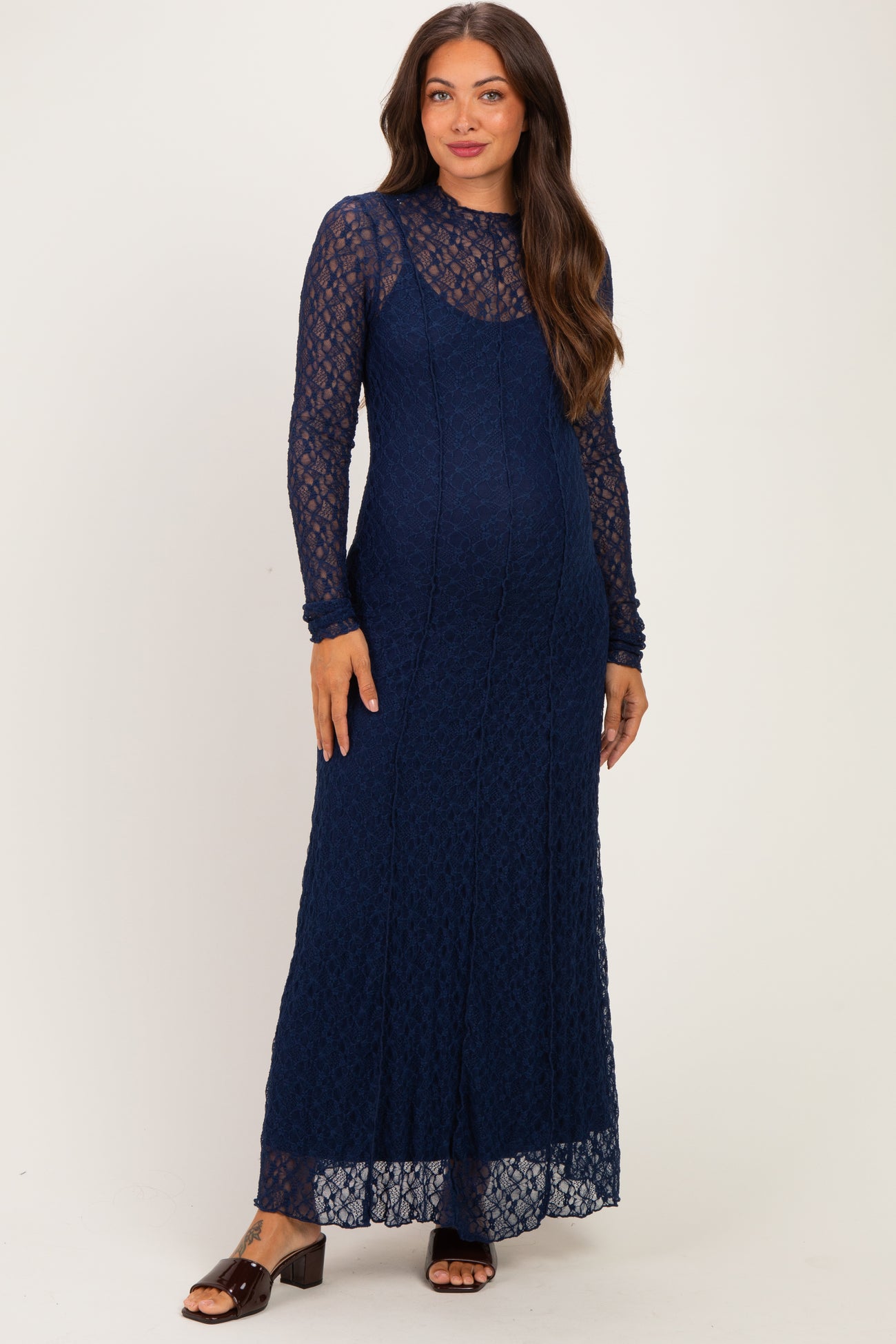 woman wearing a navy lace long sleeve maternity dress with a fitted silhouette and a flowing skirt, showing her baby bump