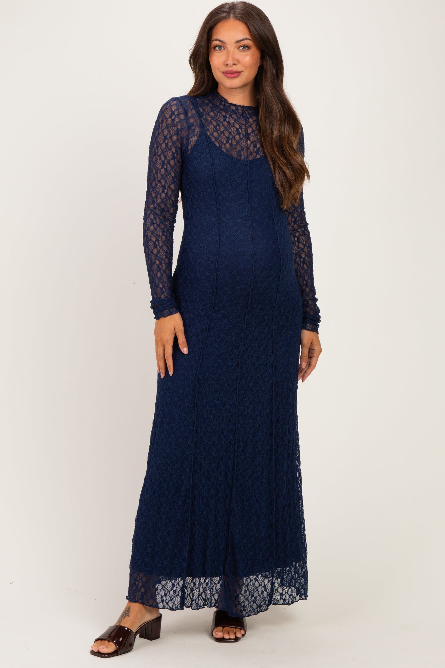 woman wearing a navy lace long sleeve maternity dress with a fitted silhouette and a flowing skirt, showing her baby bump