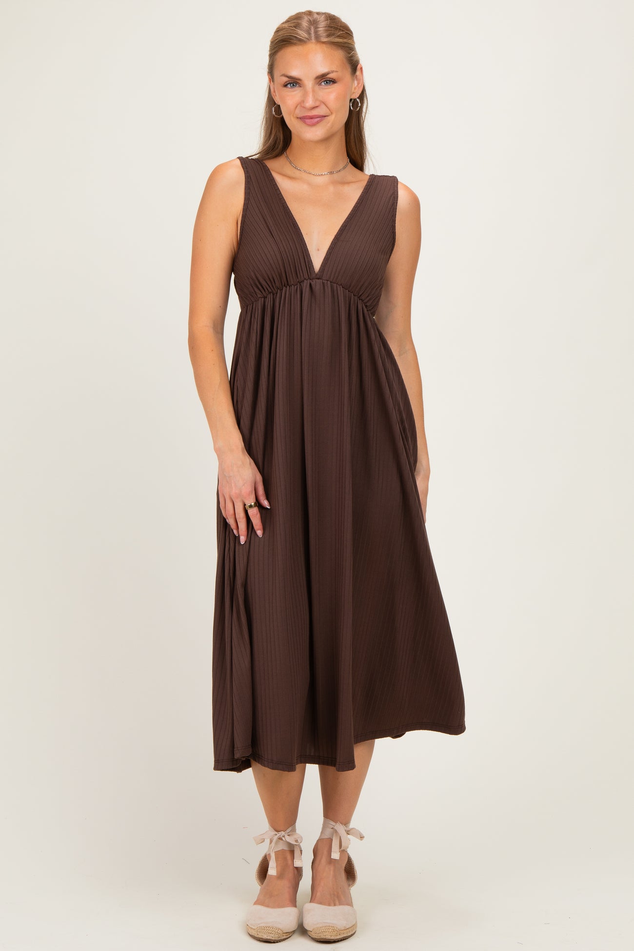 woman wearing a chocolate brown sleeveless maxi dress with a deep v-neck and flowy skirt