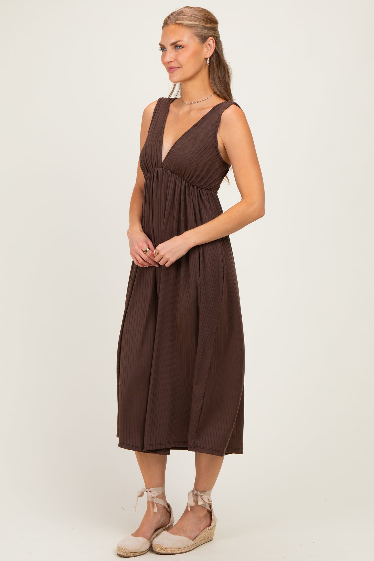 woman wearing a brown pleated midi dress with a deep v-neckline and a relaxed fit