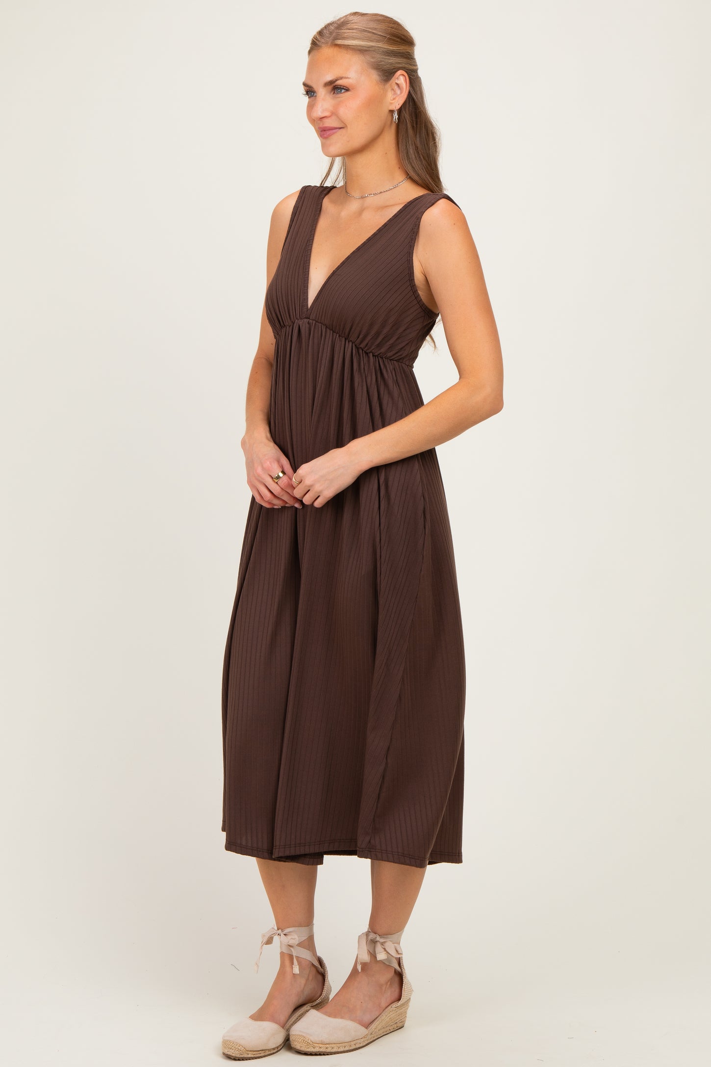 woman wearing a brown pleated midi dress with a deep v-neckline and a relaxed fit