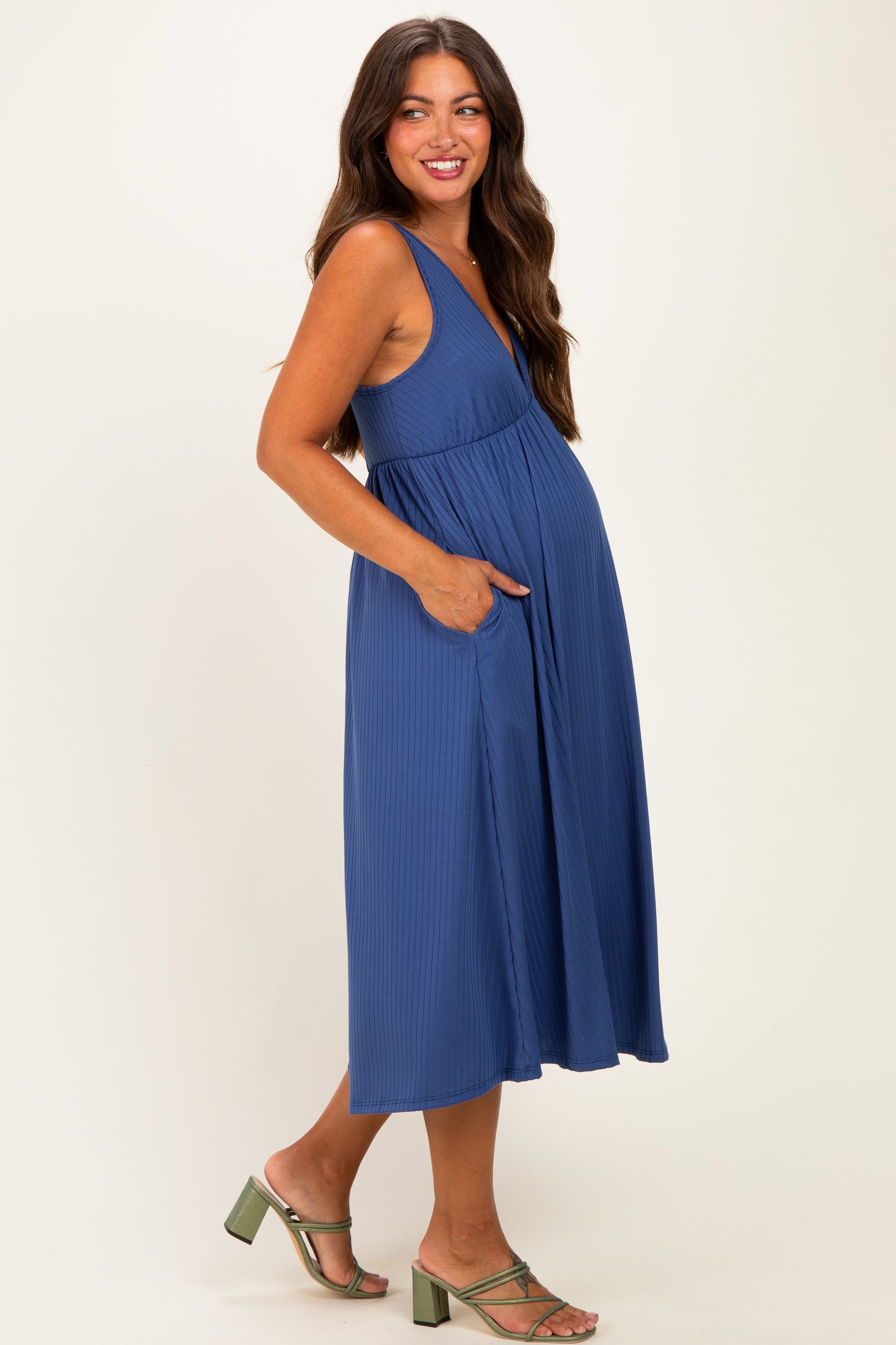 woman wearing a ribbed blue maternity dress with pockets and a visible baby bump