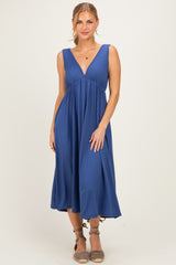 woman wearing a blue sleeveless maxi dress with a deep V-neck and a flowing skirt