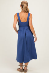 woman wearing a back view of a sleeveless blue pleated maxi dress with a fitted waist and open back design