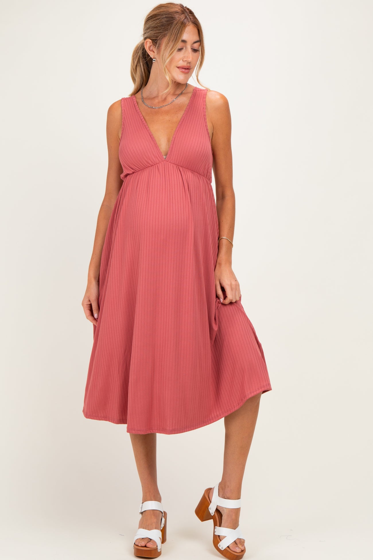 woman wearing a dusty rose sleeveless maternity dress with a deep V-neck and a flowing skirt, showcasing her baby bump