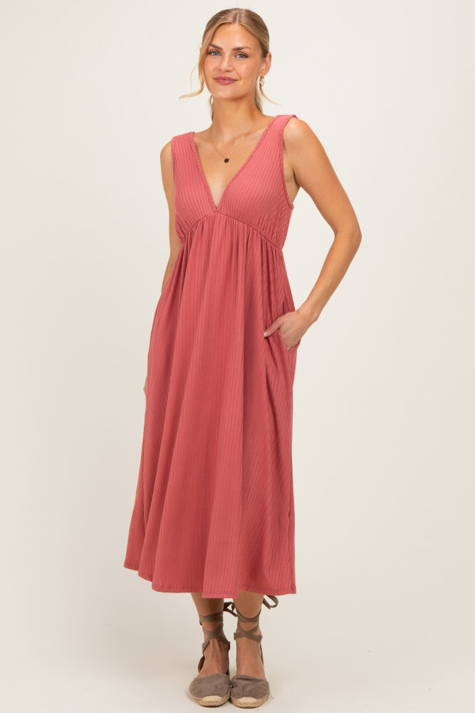 woman wearing a rust-colored sleeveless midi dress with a v-neck and pockets, standing with a slight smile