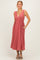 woman wearing a rust-colored sleeveless midi dress with a v-neck and pockets, standing with a slight smile