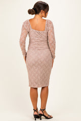 woman wearing a blush pink long sleeve lace maternity dress, fitted silhouette, showing a baby bump from the back