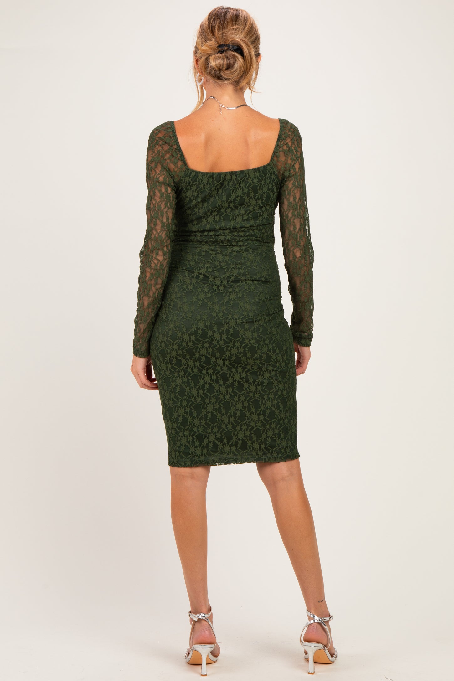 woman wearing a dark green lace long sleeve maternity dress, showcased from the back