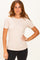 woman wearing a beige short sleeve ribbed top with a relaxed fit and standing against a neutral background