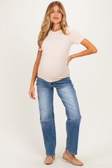 woman wearing a light pink ribbed maternity t-shirt and blue jeans, showing her baby bump