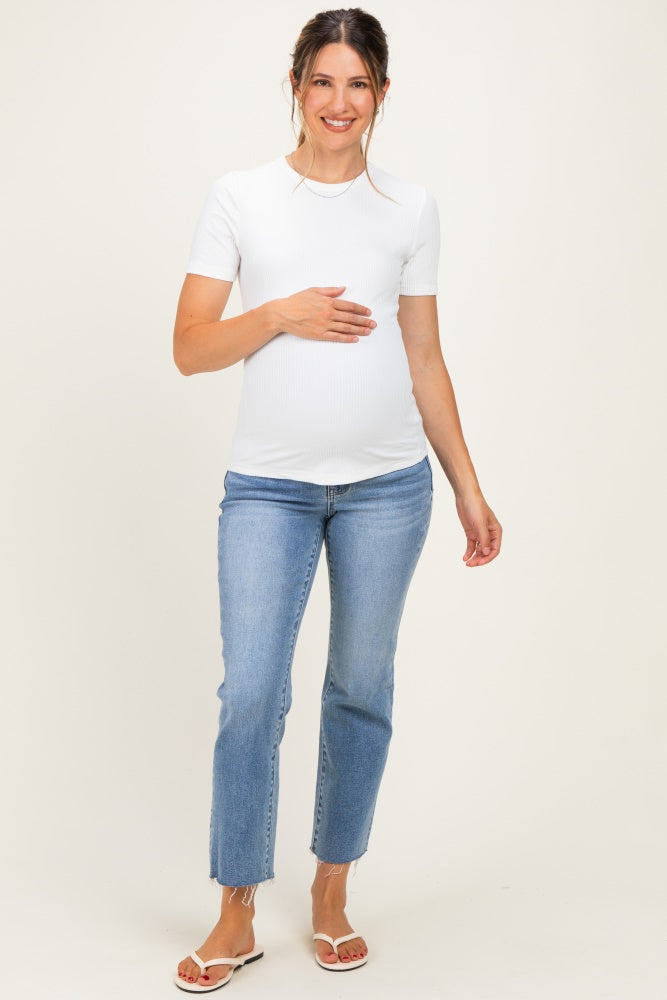 woman wearing a white short sleeve maternity top and blue jeans, holding her baby bump