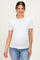 woman wearing a white short sleeve ribbed maternity top and showing her baby bump