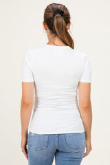 woman wearing a fitted white short sleeve maternity top, seen from the back, paired with blue jeans