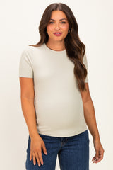 woman wearing a light grey short sleeve maternity top and showing her baby bump with blue jeans
