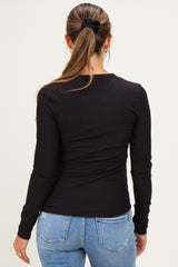 woman wearing a black long sleeve maternity top, viewed from the back with hair in a ponytail