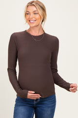woman wearing a dark brown long sleeve maternity top and holding her baby bump