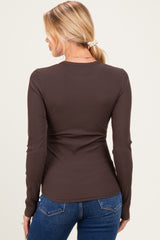 woman wearing a brown long sleeve ribbed maternity top with a fitted silhouette and wearing blue jeans