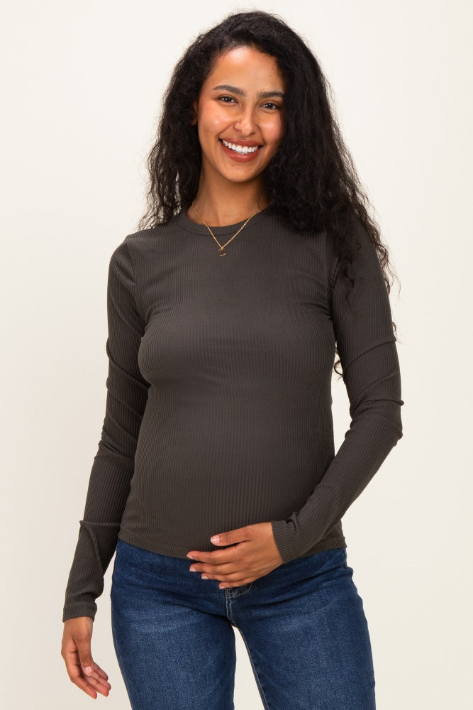 woman wearing a dark green long sleeve maternity top and holding her baby bump