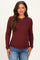 woman wearing a maroon long sleeve maternity top with ribbed texture and a baby bump visible