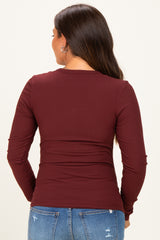woman wearing a burgundy long sleeve maternity top, showing a fitted style from the back
