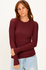 woman wearing a burgundy long sleeve ribbed top with a round neckline and fitted style