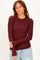 woman wearing a burgundy long sleeve ribbed top with a round neckline and fitted style