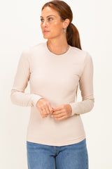 woman wearing a beige long sleeve ribbed top paired with blue jeans